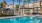 a swimming pool in front of a building with palm trees